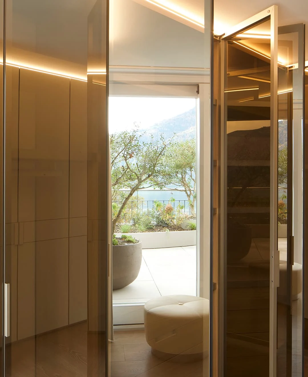 Heller Durchgang mit Glasfronten und Blick auf die Terrasse mit Pflanzen und Seesicht.