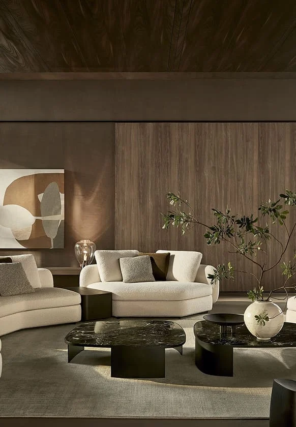 Elegantes Wohnzimmer mit hellen Sofas, dunklen Marmorcouchtischen, abstraktem Wandbild und dekorativer Pflanze vor einer warmen Holzverkleidung.