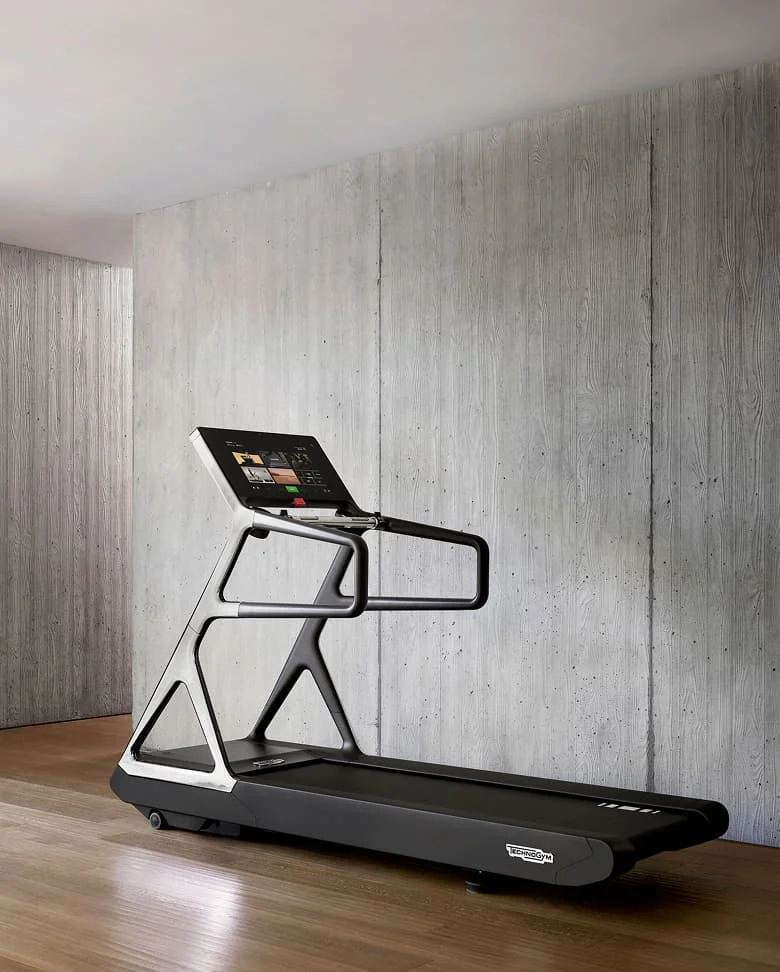 Modernes Laufband in einem Fitnessraum mit grauer Betonwand und Holzfußboden.