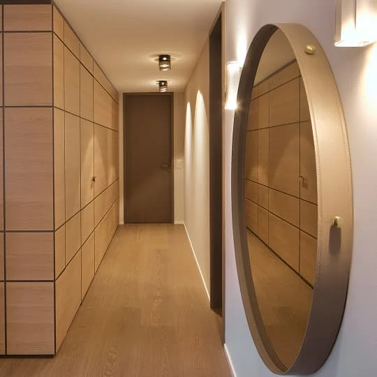flur mit holzschrank und rundem wandspiegel
