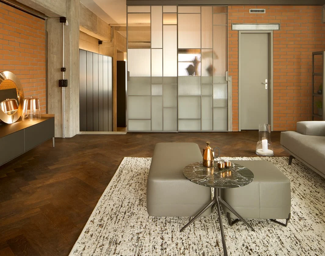 Hochwertig eingerichtetes Wohnzimmer im Industrial Stil mit Backsteinwand, Glas-Schiebetüren und modernem Mobiliar.
