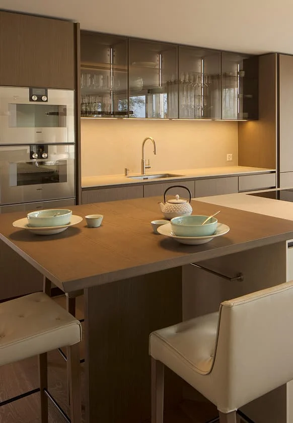 Moderne offene Küche mit Holzfronten, Kochinsel, hellen Barhockern und stilvoll gedecktem Esstisch.