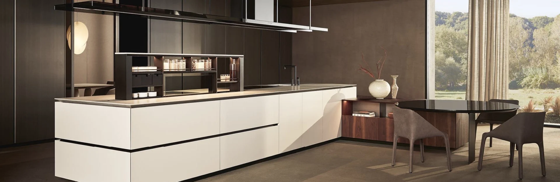 Moderne offene Küche mit großer Kochinsel, hellem Frontdesign und integriertem Regal, daneben runder Esstisch mit Stühlen und Blick ins Grüne.