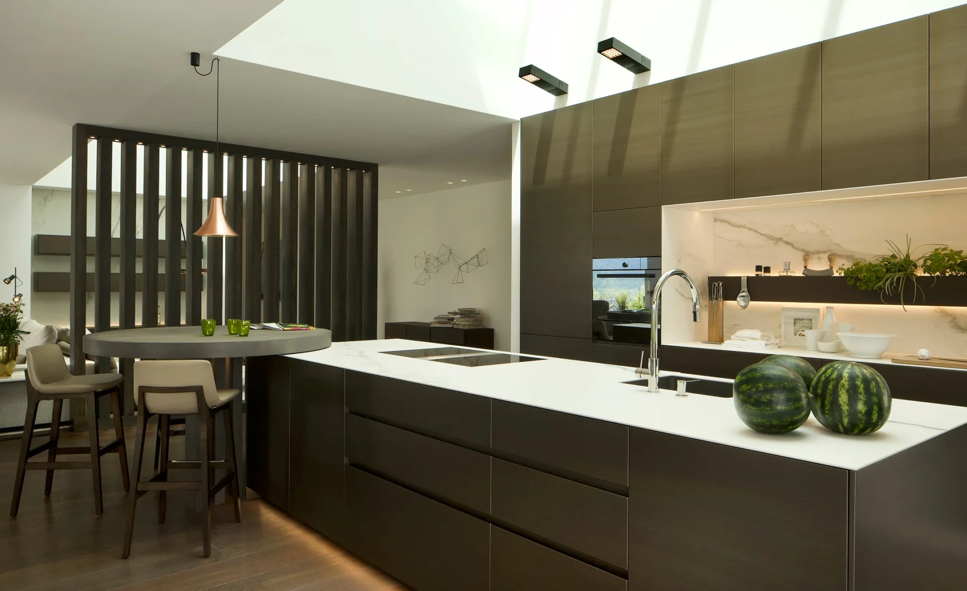 Moderne offene Küche mit großer Kochinsel, dunklen Fronten, weißer Arbeitsplatte und stilvoller Bar-Ecke.