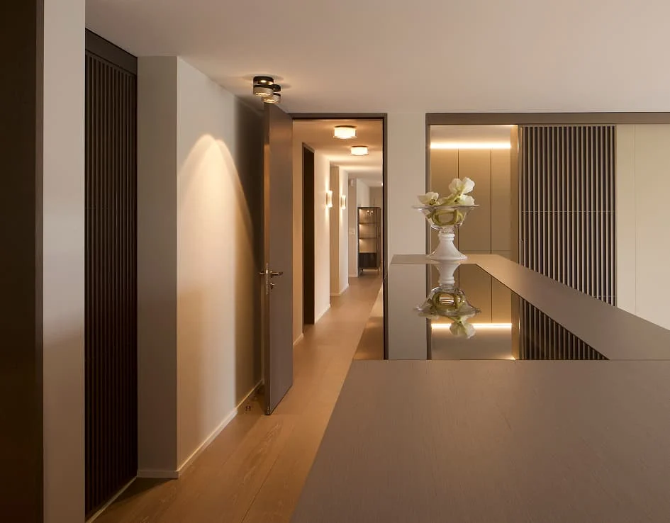 Offener Flur mit Holzlamellen, indirekter Beleuchtung und modernem Sideboard mit Glasoberfläche.