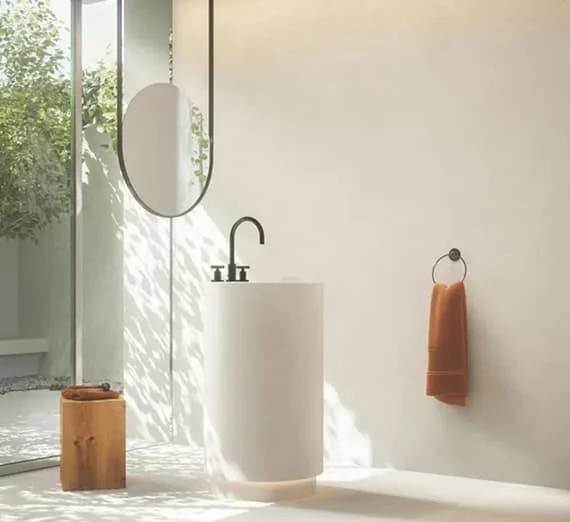 Modernes, helles Badezimmer mit freistehendem rundem Waschbecken, schwarzer Armatur, großem Spiegel und warmem Tageslicht.