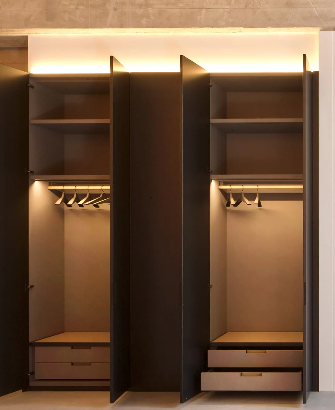 Offene Einbauschränke in modernem Design mit Kleiderstangen, Schubladen und integrierter LED-Beleuchtung.