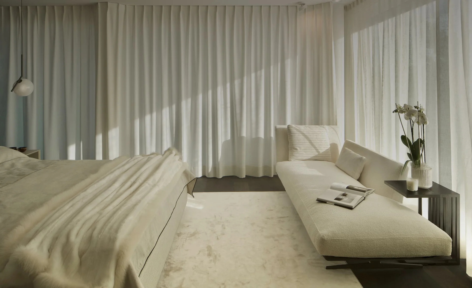 Helles Schlafzimmer mit bodentiefen Vorhängen, gepolstertem Bett, eleganter Liege und ruhiger, natürlicher Lichtstimmung.