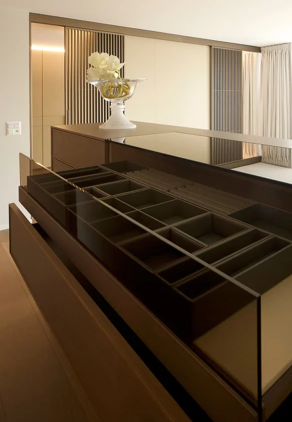 Schubladeneinsatz für Schmuck und Accessoires in einer modernen Ankleide mit Glasabdeckung und dekorativer Vase auf der Kommode.