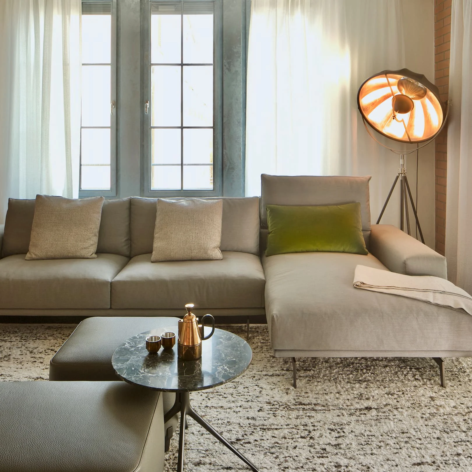 Modernes Wohnzimmer mit grauem Sofa, grünem Kissen und Design-Stehlampe im Industriestil – helles Ambiente mit natürlichen Materialien und gemütlicher Atmosphäre.