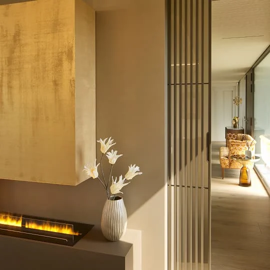 Moderner Wohnbereich mit goldfarbenem Kamin und dekorativer Vase.