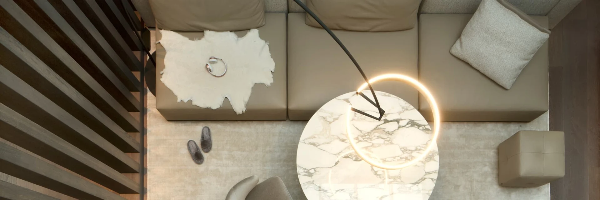 Wohnbereich aus der Vogelperspektive mit Ledersitzflächen, Fellakzent, runden Marmortisch und moderner Ringlampe – harmonische Kombination aus natürlichen Materialien und warmem Licht.